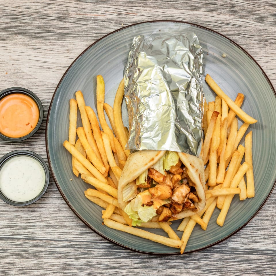 Chicken gyro served with fries and dipping sauces.